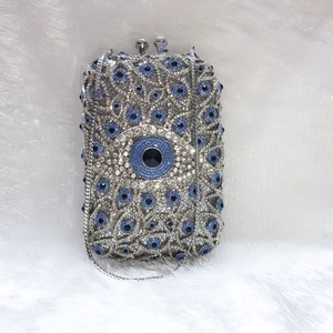 Macro shot of silver crystal clutch with blue evil eye rhinestone pattern on metal frame
