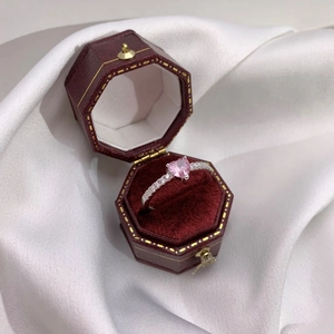 Gros plan d'une bague en zircon rose en forme de cœur dans un écrin en velours rouge
