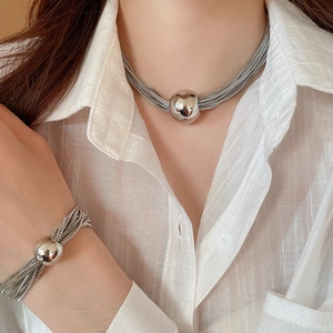 Detail of silver multi-layer chain necklace and bracelet worn on a white shirt