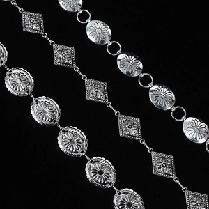 Detailed macro view of geometric metal waist chains with floral and diamond pattern links
