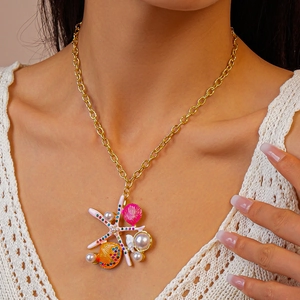 Detailed close-up of a beach-style gold necklace with starfish, shells, and pearls