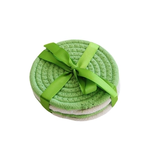 Three round braided cotton coasters in green and beige tied with a green ribbon gift wrap