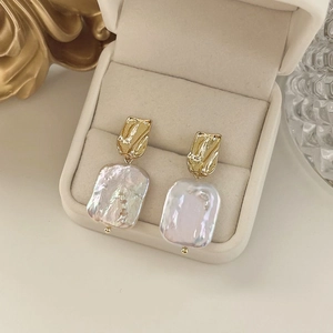 Detailed view of handmade baroque freshwater pearl earrings in gold setting on velvet