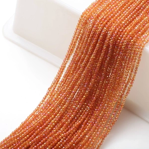 Close-up of orange faceted glass beads on cotton thread for DIY jewelry making
