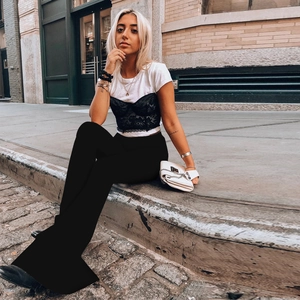 Outdoor street style shot of high-waisted black flare pants for women on model