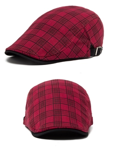 Detail view of red and black plaid beret hat with adjustable strap and black brim