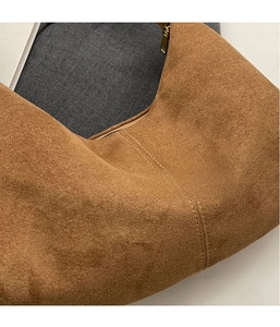 Close-up of brown suede hobo bag detailing double stitching and smooth metal zipper