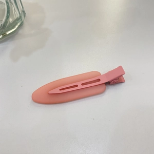 Detail of pink candy-colored hair clip with translucent oval plate and matching metal duckbill clip
