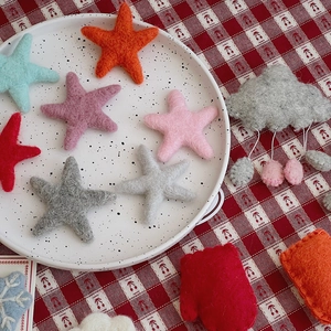 Miniature handmade wool felt stars and snowflake crafts on a rustic tablecloth