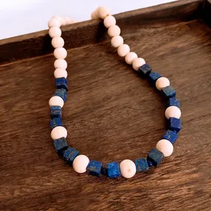 Boho wood bead and lapis lazuli beaded necklace displayed in a dark rustic wooden tray