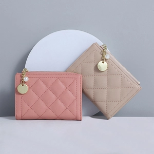 Close-up of pink and khaki quilted wallets with pearl and gold chain zipper charms