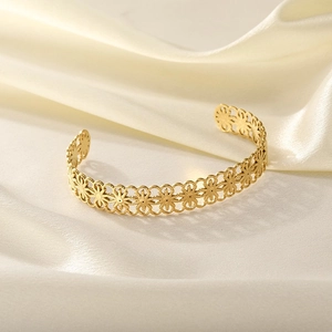 Detail view of a gold-plated stainless steel cuff featuring hollow flower patterns
