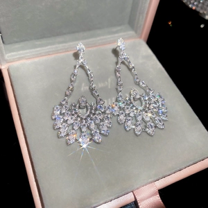 Detailed view of silver dangle earrings with teardrop zircons on grey velvet background