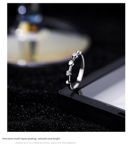 Macro detail of silver twisted ring band with sparkling zircon heart accents and fine plating