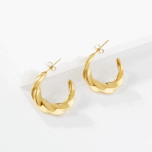 Fashionable 18K gold-plated stainless steel twisted C-shaped hoop earrings on a marble base