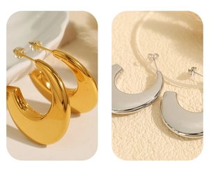 Macro view of gold and silver C-shaped titanium steel earrings with polished finish