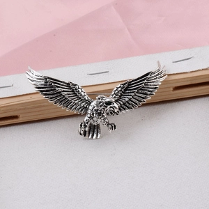 Detailed macro view of an eagle brooch featuring textured feathers and green gemstone eyes