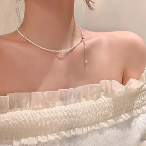 Detail of gold-plated pearl necklace with long tassel pendant on model's neck