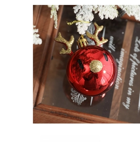 Artistic close-up of a red Christmas reindeer ornament with glitter on a pine background