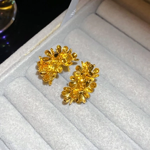 Close-up of golden floral cluster stud earrings in a grey velvet jewelry box