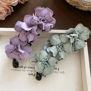 Détail de barrettes banane à fleurs en tissu violet et vert sur un plateau