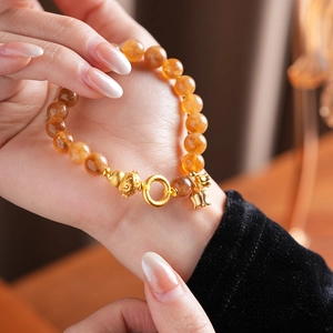 Dettaglio del bracciale di citrino con ciondolo a loto sul polso di una donna