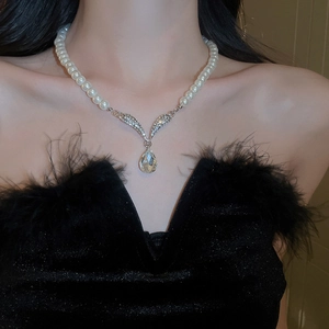 Macro shot of pearl necklace with V-shaped diamond wings and teardrop crystal on model