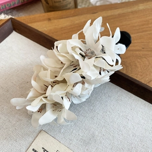 Detailed view of white fabric floral hair clip with intricate petal design and banana clip