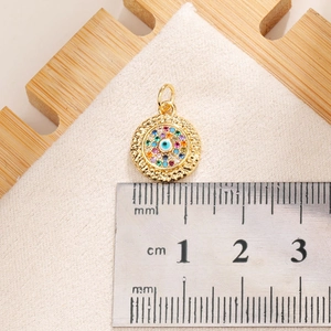 Macro view of a 15mm gold Evil Eye pendant with colorful zircons and a metric ruler