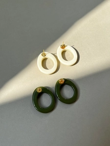 Detailed view of geometric resin earrings with engraved gold metal plates and smooth finish