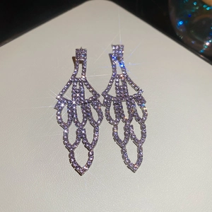 Macro detail of silver-purple tassel earrings with sparkling rhinestones and star flare effect