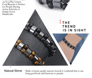 Detail shot of natural matte stone and tiger eye beaded bracelets on a male wrist