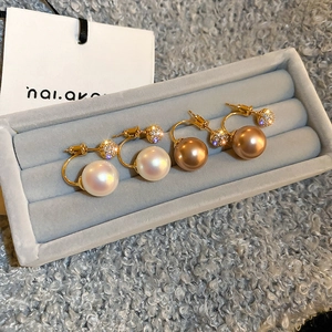 Detail of geometric pearl earrings with zircon studded gold balls on velvet tray
