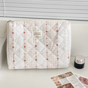 Detailed close-up of quilted floral makeup bag with today mood fabric label and zipper