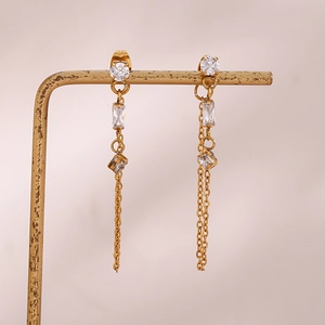 Macro shot of long gold tassel earrings with square and round zircon on a metal stand
