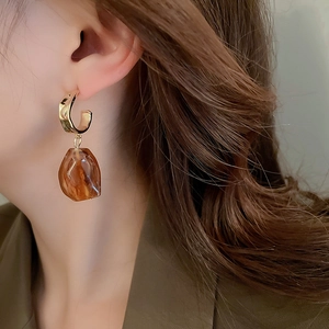 Detail of amber resin drop earrings with gold metal hoops worn by a model