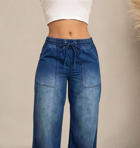 Detail van blauwe denim broek met wijde pijpen, elastische taille met trekkoord en grote zakken