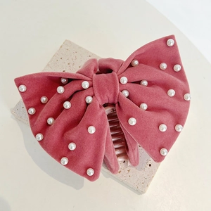 Close-up of pink velvet bow hair claw clip with white pearl beads on stone base