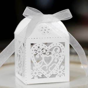 Macro detail of laser-cut heart pattern on white wedding favor box with ribbon