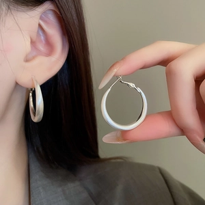 Close-up of matte silver large hoop earrings worn by a model in a modern style