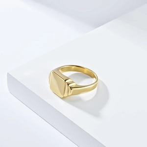 Macro shot of 18K gold plated square signet ring with high polished finish on white blocks