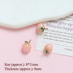 Detail of three mini pink peach pendants with green leaves for DIY jewelry making