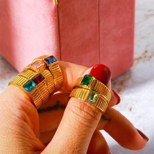 Close-up of gold-plated birthstone rings with vertical ridges and emerald-cut gems