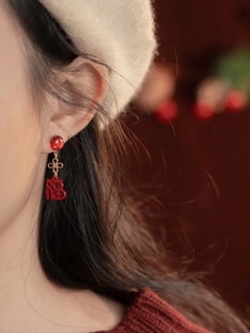 Gros plan de boucles d'oreilles Fu rouges avec nœuds chinois dorés sur un mannequin
