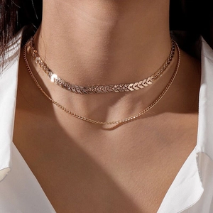 Close-up of a double-layered gold fishbone chain necklace with minimalist arrow texture