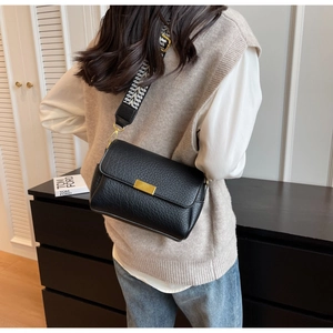 Détail du sac bandoulière en cuir noir grainé avec sangle large géométrique