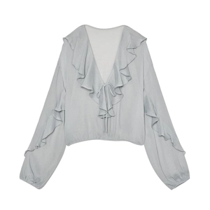 Detailed view of V-neckline with ruffle trim and drawstring tie on light gray blouse