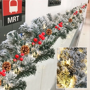 Detail of 9ft snow-flocked Christmas garland with red berries, pine cones and LED lights