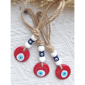 Macro detail of red glass evil eye pendants with rustic jute rope for home or car decor