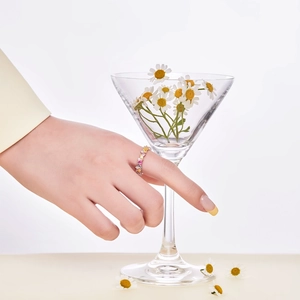 Detail of colorful cubic zirconia eternity ring on a hand with a daisy glass background
